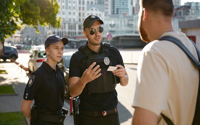 Patrol policeman and policewoman checking personal documents of citizen on city street